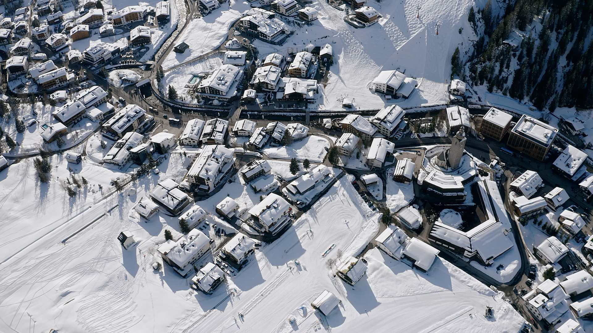 Winterliches Bergdorfpanorama Verschneites Bergdorf aus der Luftansicht mit traditionellen Häusern und malerischer Landschaft.